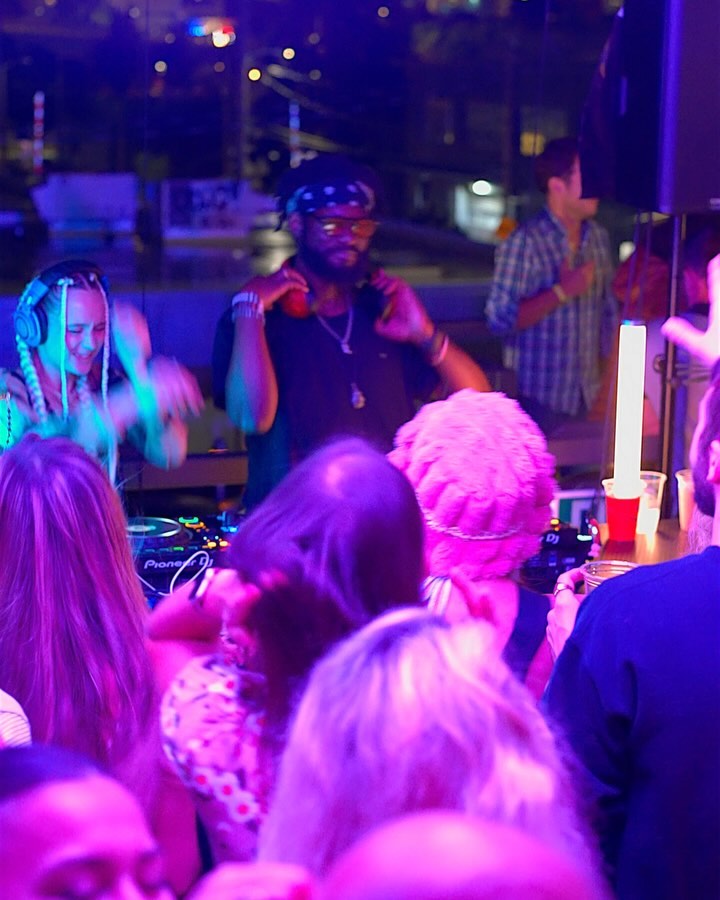 pink blue and orange lights with djs and dancers enjoying themselves.