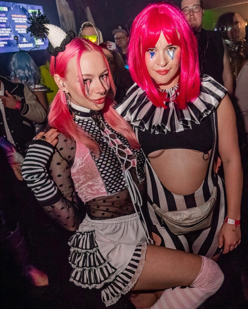 two girls with black and white clown outfits on and pink wigs