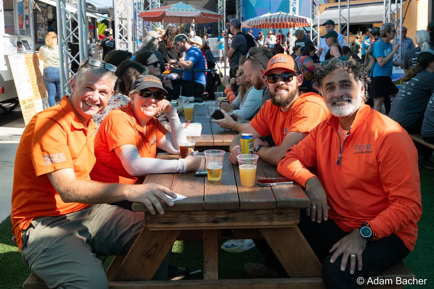 four workers in orange shirts enjoying food and beers in the courtyard. 